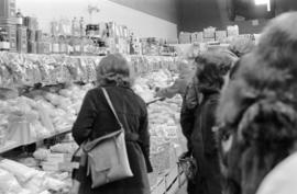 Interior of unidentified grocery store with shoppers, clerks, and stock