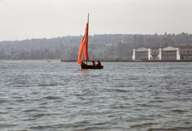 Small sailboat with two passengers, sailing near [?]