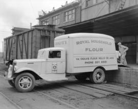 [Man loading Royal Household flour onto an] Ogilvie Flour Mill truck [at 1280 Homer Street]