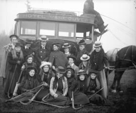 [Group of women with field hockey sticks assembled in front of Hotel Vancouver's horsedrawn bus]