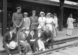 [Two soldiers with civilian friends/relatives at railway platform]