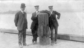 [Three men near an old wooden pile on the old C.P.R. dock]