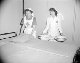 [Red Cross workers making a bed for a blood donor clinic]