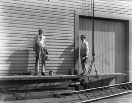 [Two men painting a Vancouver wharf]
