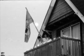 Family on balcony holding Centennial flag