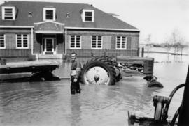Dick Neufeld [standing in water with tractor]