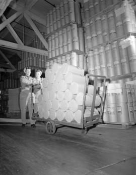 [Two women pushing a handcart loaded with paper] rolls [at] Pacific Mills