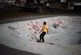 [Man skateboarding in skateboard park bowl]