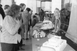 People viewing birthday cakes on display