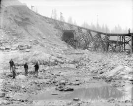 [Men standing in partially excavated area of Coquitlam Dam construction site]