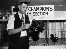 Man holding dark-colored chicken in poultry competition