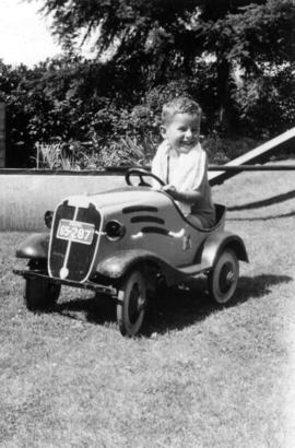 John Banfield in toy car on lawn