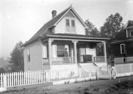 [Woman standing at front porch, and girl standing at front gate of house in Grandview-Cedar Cotta...