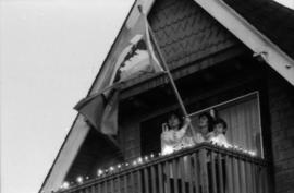 Family on balcony holding Centennial flag