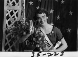 Portrait of Nancy Hansen, Miss P.N.E. 1954, posing with trophy and flowers