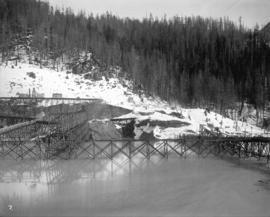 [Partially constructed Coquitlam Dam, looking east at edge of tree covered hillside]