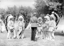 [RCMP officer handing baseball equipment to Stoney Indians at the Calgary Stampede grounds]