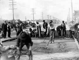 [Men doing road work on] Main St. - placing cushion