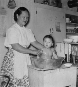 Gum May Yee bathing her son Vernon in the café kitchen in Naicam, Saskatchewan