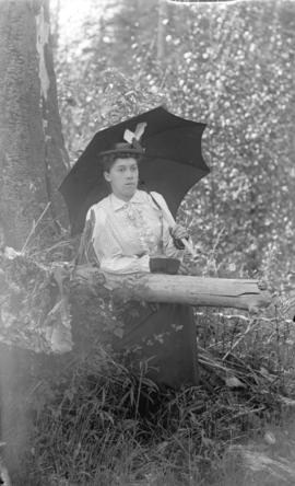 [J.E. Hall standing among trees with umbrella]