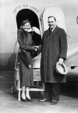 Alderman Halford Wilson shaking hands with unidentified woman in front of United Air Lines aircraft