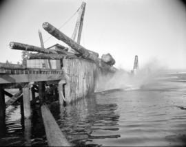 [Logs falling off a wharf into the water at H.R. MacMillan Co.]