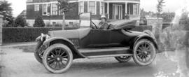 [Unidentified woman sitting in a car in front of a house]