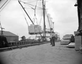 [Boxes of food being loaded onto a cargo boat at the Evans, Coleman and Evans, Ltd. pier]
