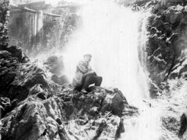 [Unidentified man sitting by a waterfall]