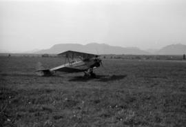 [View of biplane in field]
