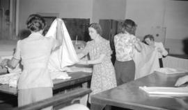 [Women folding sheets at Nelson's laundry]