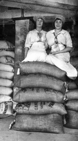 Two women seated on bags of sugar