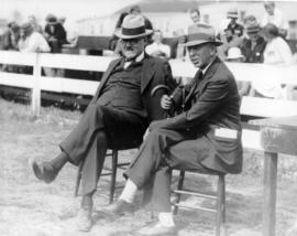 Two unidentified men sitting on fairgrounds