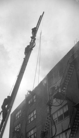 [Firemen on tower ladder at scene of a building fire]