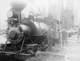 [Men standing beside railway engine pulling logs]