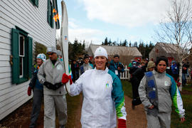 Day 24 Torchbearer 59 Cassie Campbell-Pascall carrying the flame in front of Green Gables House i...