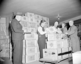 [People checking and loading Canadian Red Cross Society food supplies onto a cart]