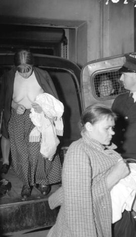 [Partially naked Doukhobor women getting out of a patrol wagon at the police station]