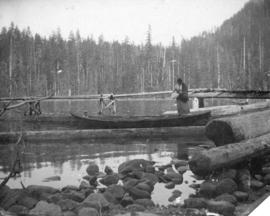 [A woman stepping into a canoe at a logging camp]