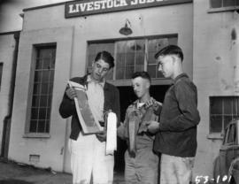 Boys holding 4-H competition prizes outside of Livestock Judging building