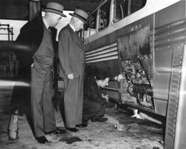 [E.W. Arnott and George Miller watch a mechanic inspect a new B.C. Electric Railway bus]