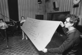 Two men holding up lyrics on banner