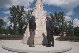 Two men standing at a public monument to Chinese Canadians in Calgary