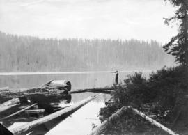 [A man firing a rifle over] Lynn Lake in Lynn Valley