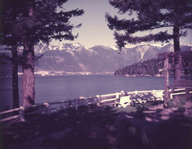 [A couple sitting on a bench overlooking the water towards the mountains]