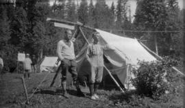 Two men standing by a tent at the campsite