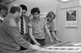Toni Onley (left) and group examine Centennial Art Series print at Agency Press
