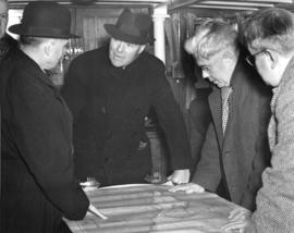 [Commander A.H. Reid, K.J. Burns and His Worship J. Lyle Telford looking at a navagation map on b...
