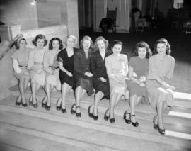 [Group portrait of women sitting on steps inside a building]