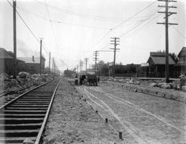 [Men standing next to horse drawn cart, spreading gravel for reconstruction of streetcar lines at...